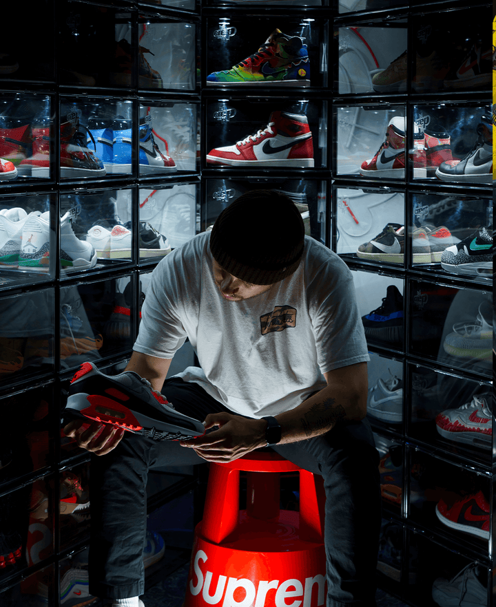 Man Holding a Sneaker Surrounded by Sneakers Inside Crep Protect 3.0 sneaker box