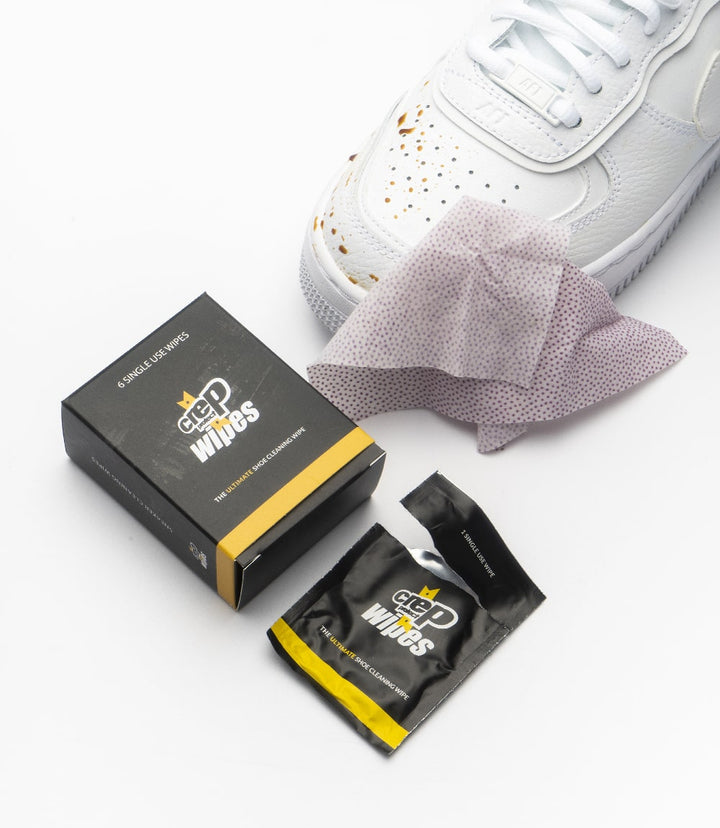 Fresh sneakers beside Crep Protect wipes on a white surface for cleaning.
