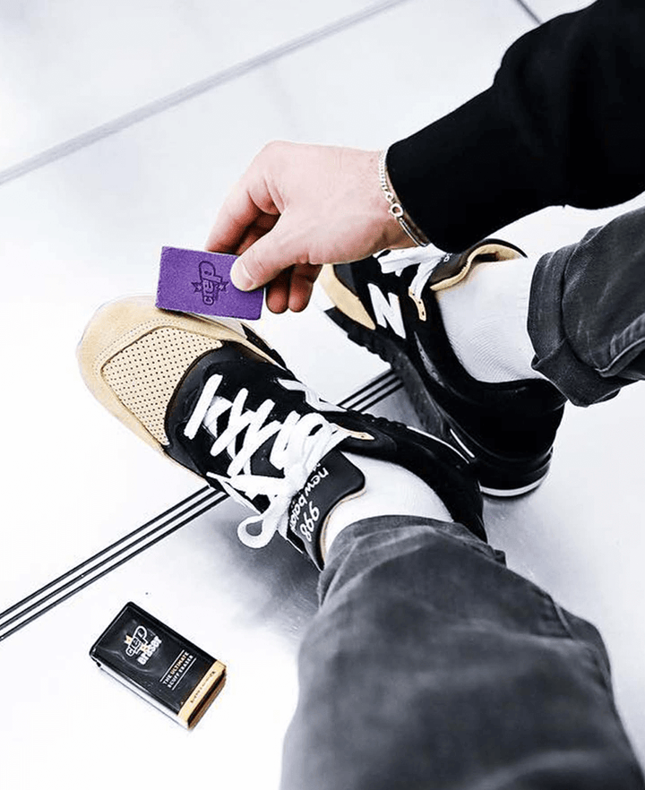 Man using Crep Protect eraser to clean Nike sneakers for maintenance.