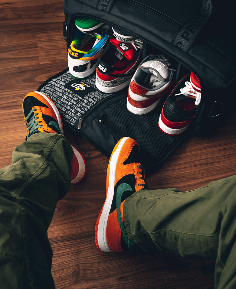 Man wearing sneakers sits, Crep Protect sneaker care bag prominently displayed in front of him.